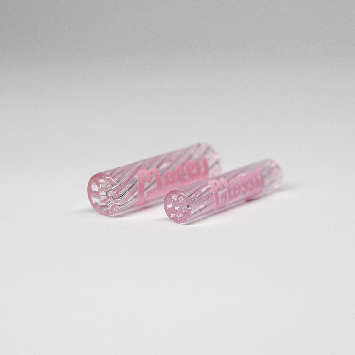 Visueller Vergleich der Glas Tip Größen: Der 8mm Glassfilter (links) und der 6mm Slim Glas Tip (rechts) von Glossy Genetics nebeneinander auf neutralem Hintergrund. Beide wiederverwendbaren Filter zeigen das pinke 'Glossy'-Logo.